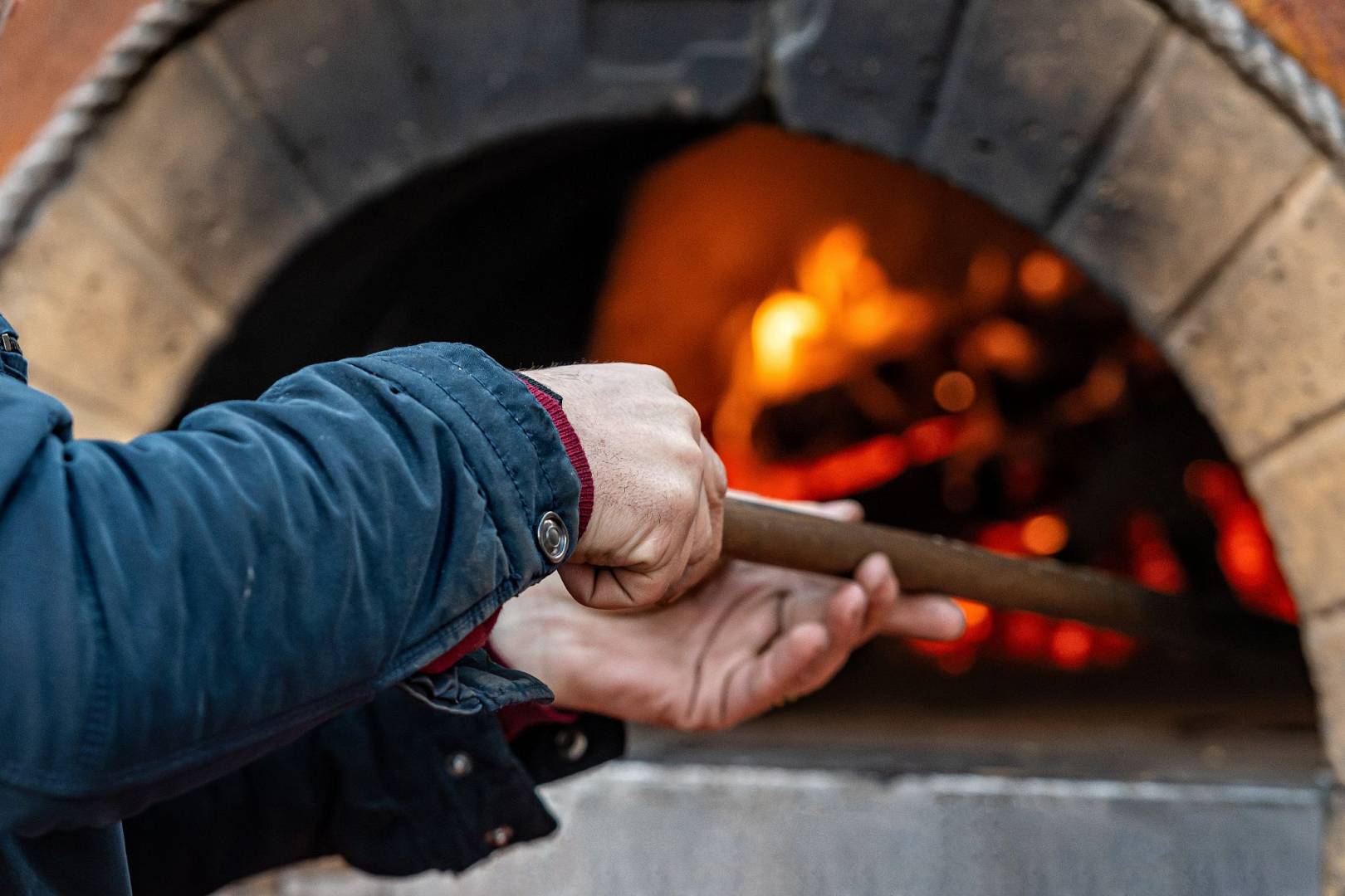 mężczyzna obsługujący ogrodowy piec do pizzy